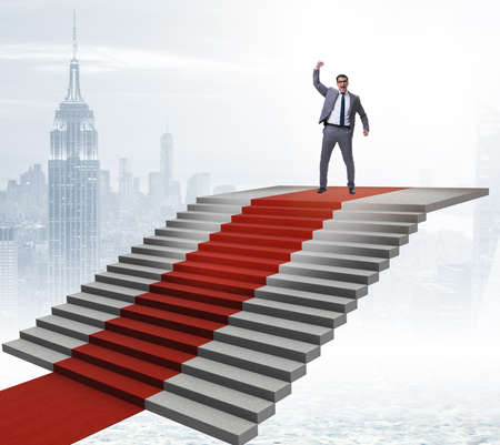 Young businessman climbing stairs and red carpetの写真素材