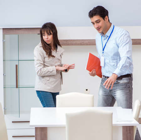 Salesman explaining to woman customer at furniture storeの写真素材