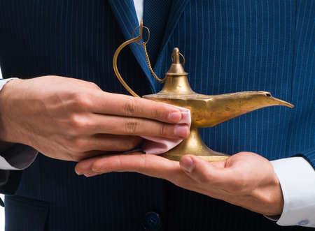 Businessman with magic lamp isolated on whiteの写真素材