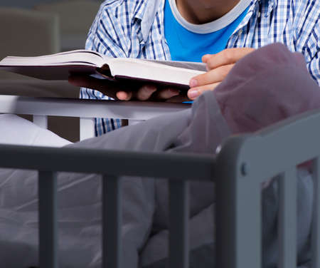 Young student doing homework and looking after newborn babyの写真素材