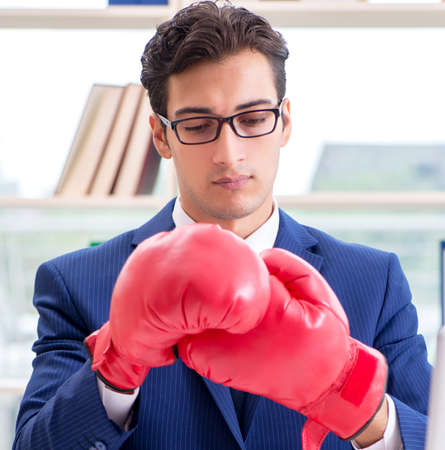 Businessman with boxing gloves angry in officeの写真素材