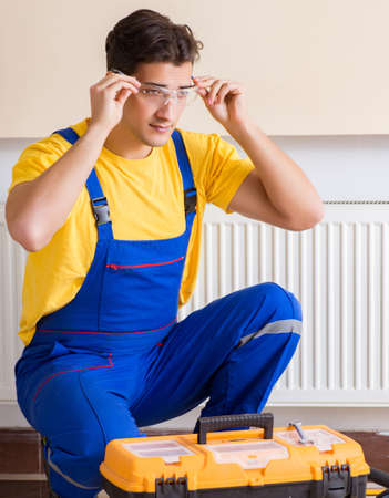 Young repairman contractor repairing heating panelの写真素材