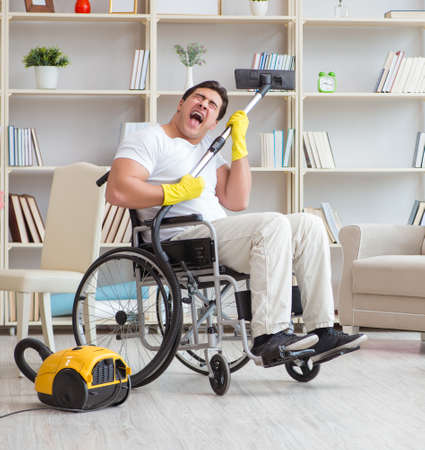 Disabled man with vacuum cleaner at homeの写真素材