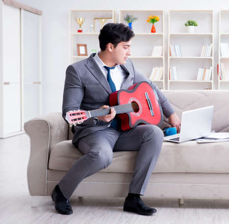 Businessman playing guitar at homeの写真素材