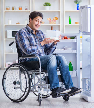 Young disabled injured man opening the fridge doorの写真素材