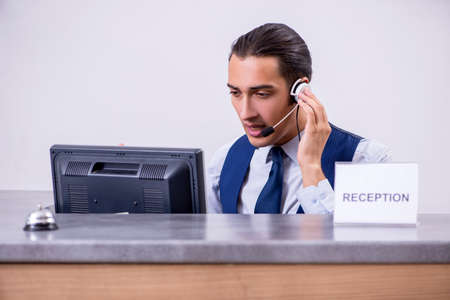 Young man receptionist at the hotel counter