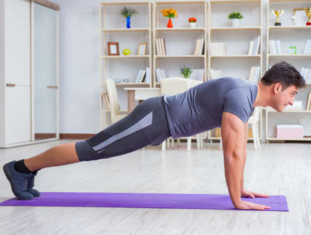 Young man exercising at home in sports and healthy lifestyle conの写真素材