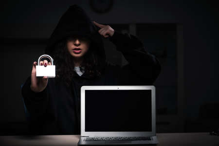 Female hacker hacking security firewall late in officeの写真素材
