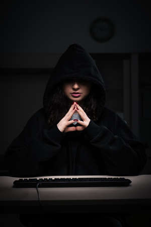 Female hacker hacking security firewall late in officeの写真素材