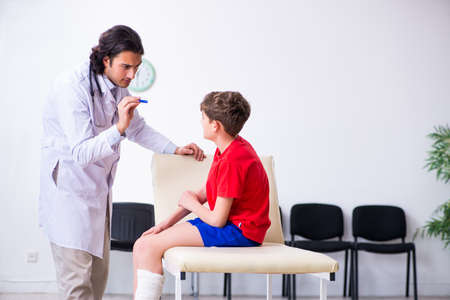 Leg injured boy visiting young doctor traumatologistの写真素材