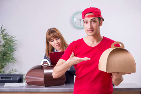 Young male courier delivering cake to reception