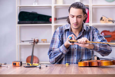 Young handsome repairman repairing violinの写真素材