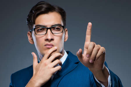 Businessman pressing virtual buttons on gray backgroundの写真素材