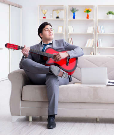 Businessman playing guitar at homeの写真素材