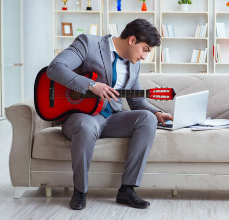 Businessman playing guitar at homeの写真素材
