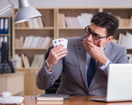 Businessman gambling playing cards at workの写真素材