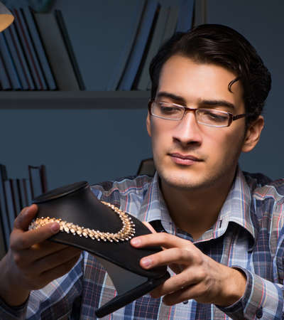 Young male jeweller working at night in his workshop