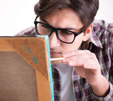 Young male artist drawing pictures in bright studio