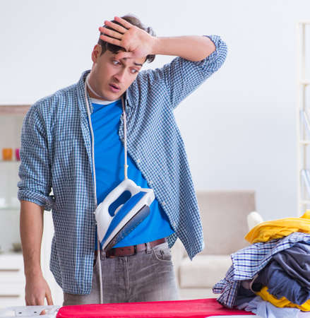 Young man husband doing clothing ironing at homeの写真素材