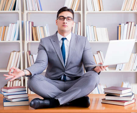 Businessman student in lotus position meditating with a laptop iの写真素材