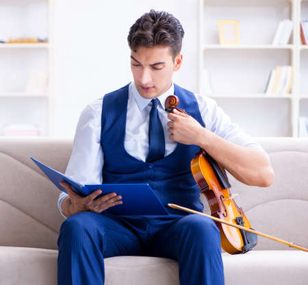 Young musician man practicing playing violin at homeの写真素材