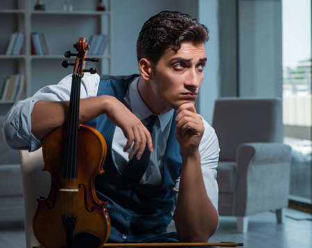 Young musician man practicing playing violin at homeの写真素材