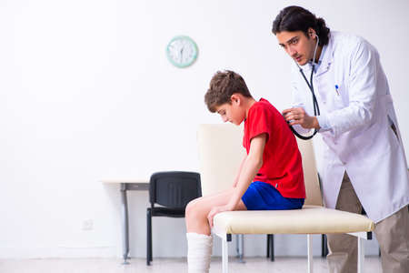 Leg injured boy visiting young doctor traumatologistの写真素材