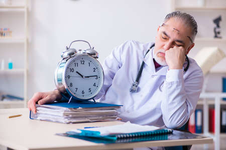 Old male doctor working in the clinicの写真素材
