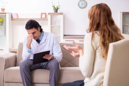 Young female patient discussing with male psychologist personalの写真素材