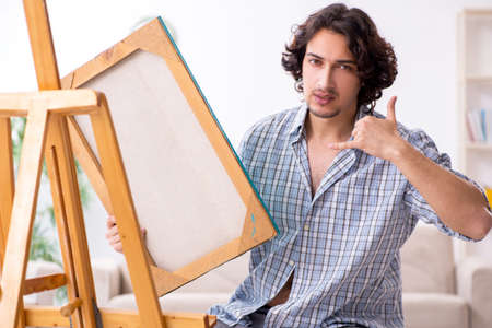 Young handsome man enjoying painting at home
