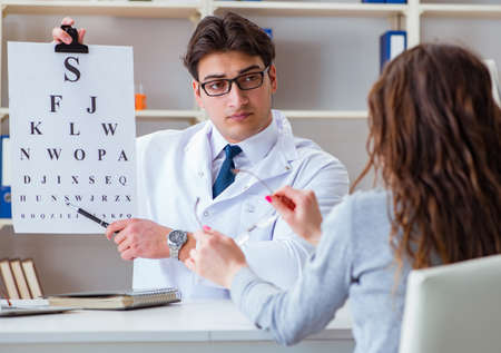 Doctor optician with letter chart conducting an eye test checkの写真素材
