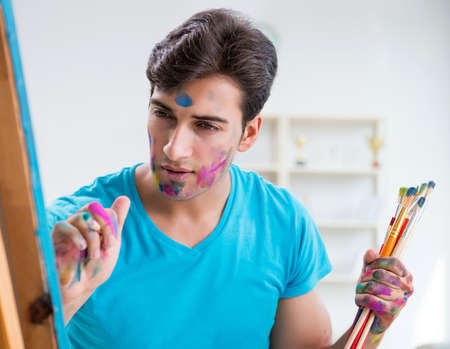 Young funny artist working on new painting in his studioの写真素材
