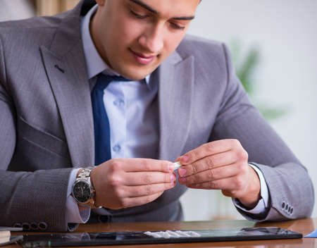 Drug addict businessman in the officeの写真素材