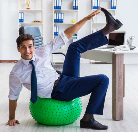 Young businessman doing sports stretching at workplaceの写真素材