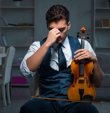 Young musician man practicing playing violin at homeの写真素材