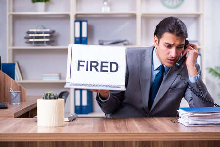 Young male employee being fired from his workの写真素材