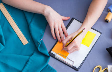 Woman tailor working on a clothing sewing stitching measuring fa