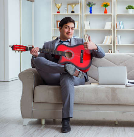 Businessman playing guitar at homeの写真素材