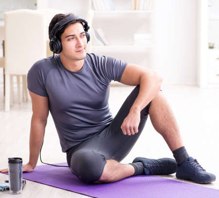 Man doing sports at home and listening to musicの写真素材