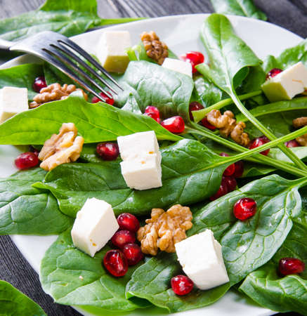 Spinach salad with nuts and apples served on tableの写真素材