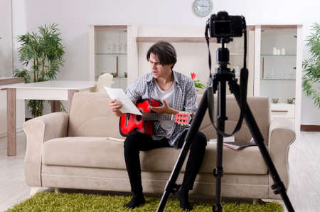 Young guitar player recording video for his blogの写真素材