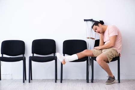 Young injured man waiting for his turn in hospital hallの写真素材