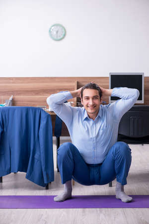 Young handsome businessman doing exercises at workplaceの写真素材