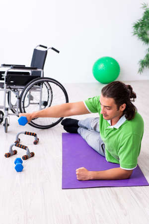Young man in wheel-chair doing exercises indoorsの写真素材