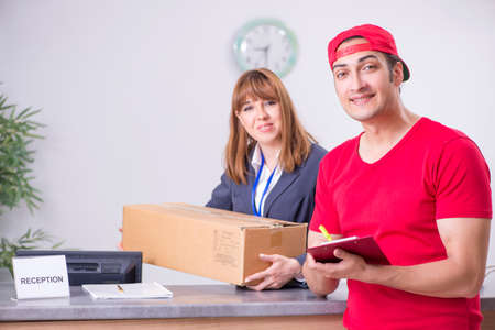 Young male courier delivering box to hotels reception