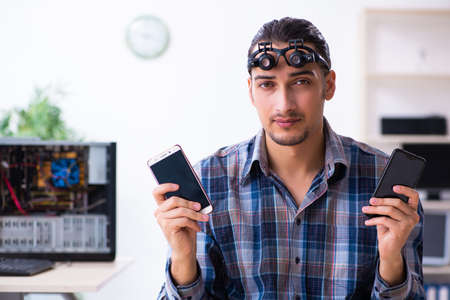 Young handsome technician repairing mobile phone