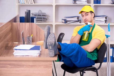 Young male contractor cleaning the officeの写真素材