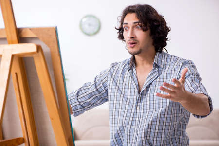 Young handsome man enjoying painting at homeの写真素材