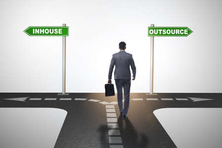 Businessman at crossroads deciding between outsourcing and inhouの写真素材
