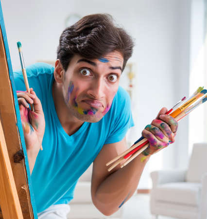 Young funny artist working on new painting in his studioの写真素材